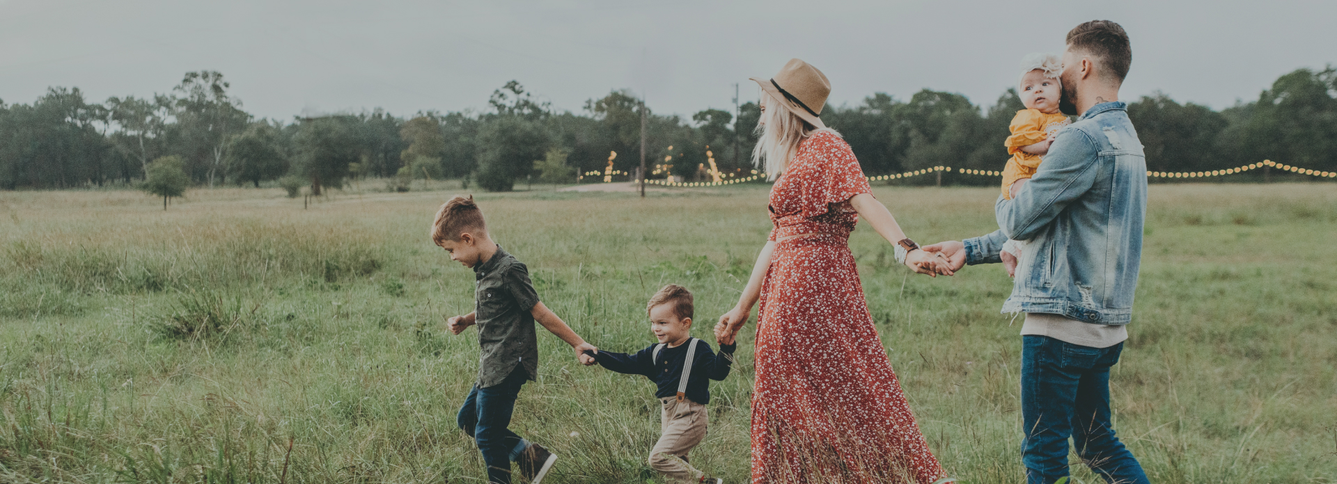 A young family holding hands and playing in a field