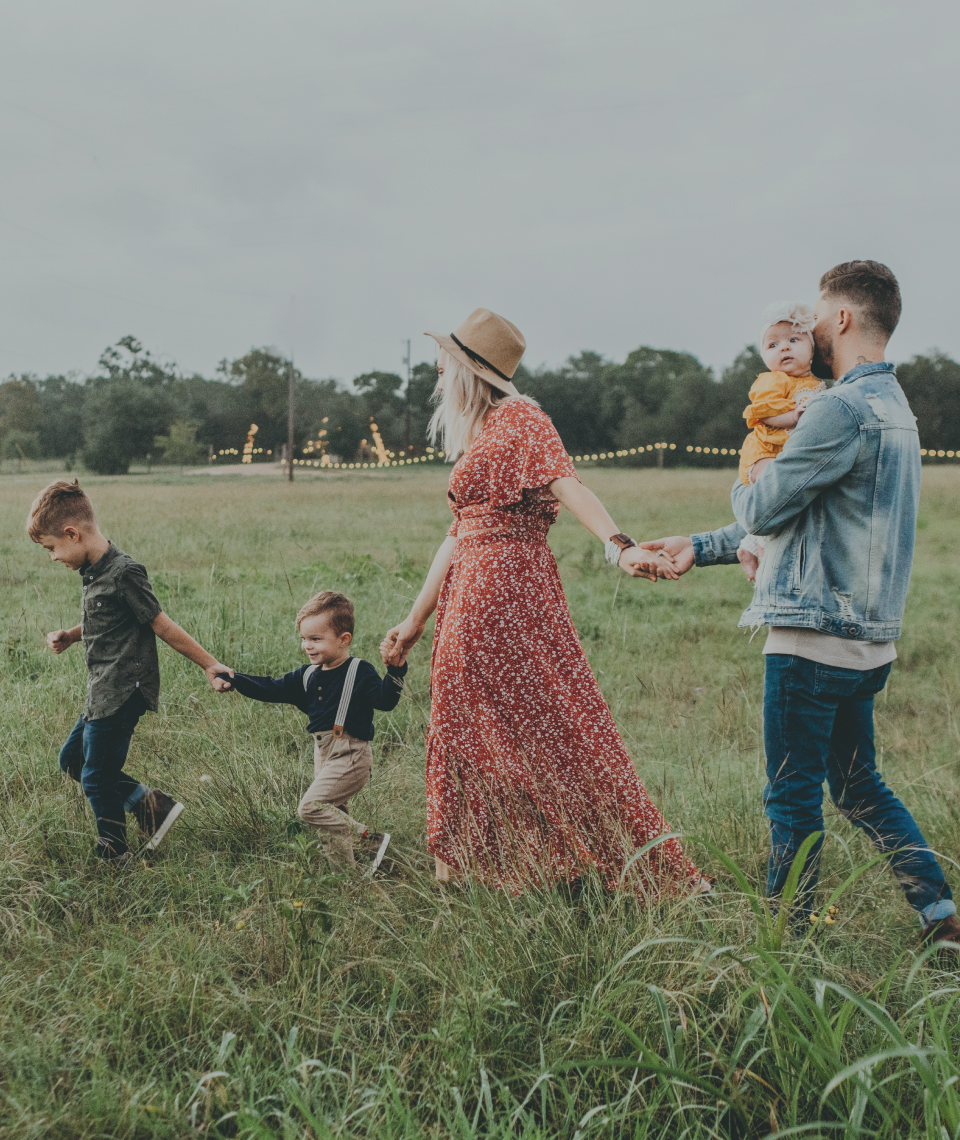A young family holding hands and playing in a field