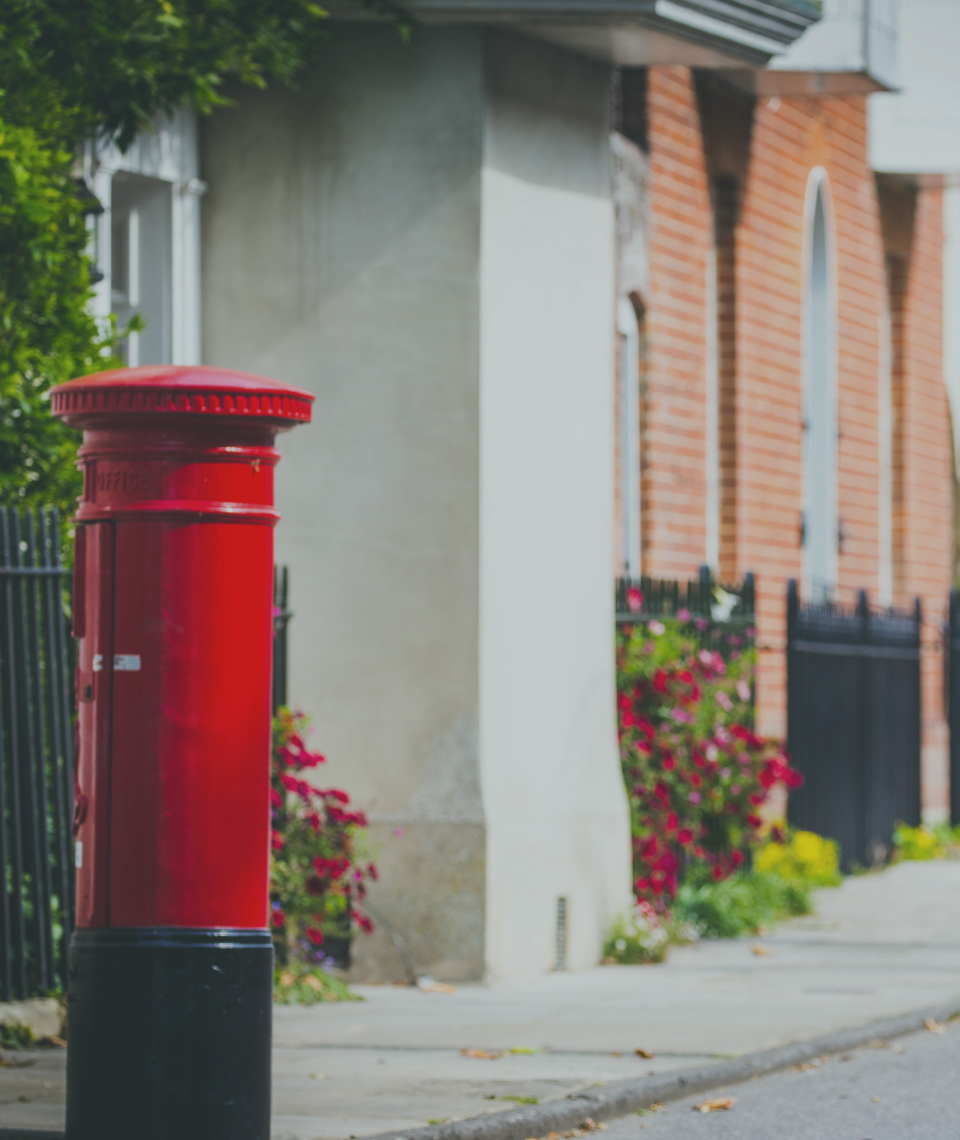 A red postbox on a sunny street